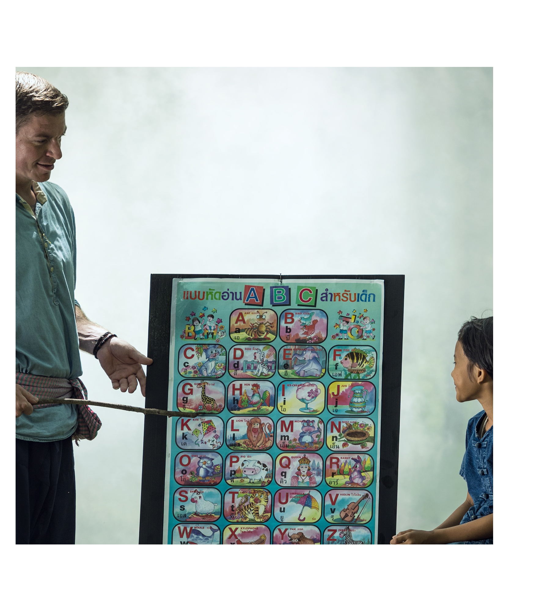 adulto señalando dibjos en una pizara mientras un niño atiende