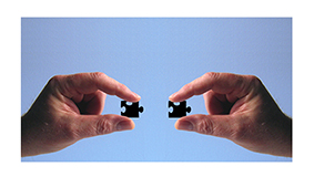 manos uniendo dos piezas de puzle