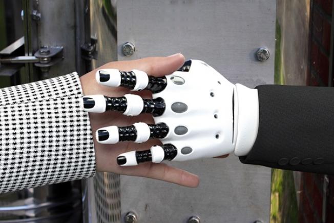 mano humana y mano mecánica estrechándose